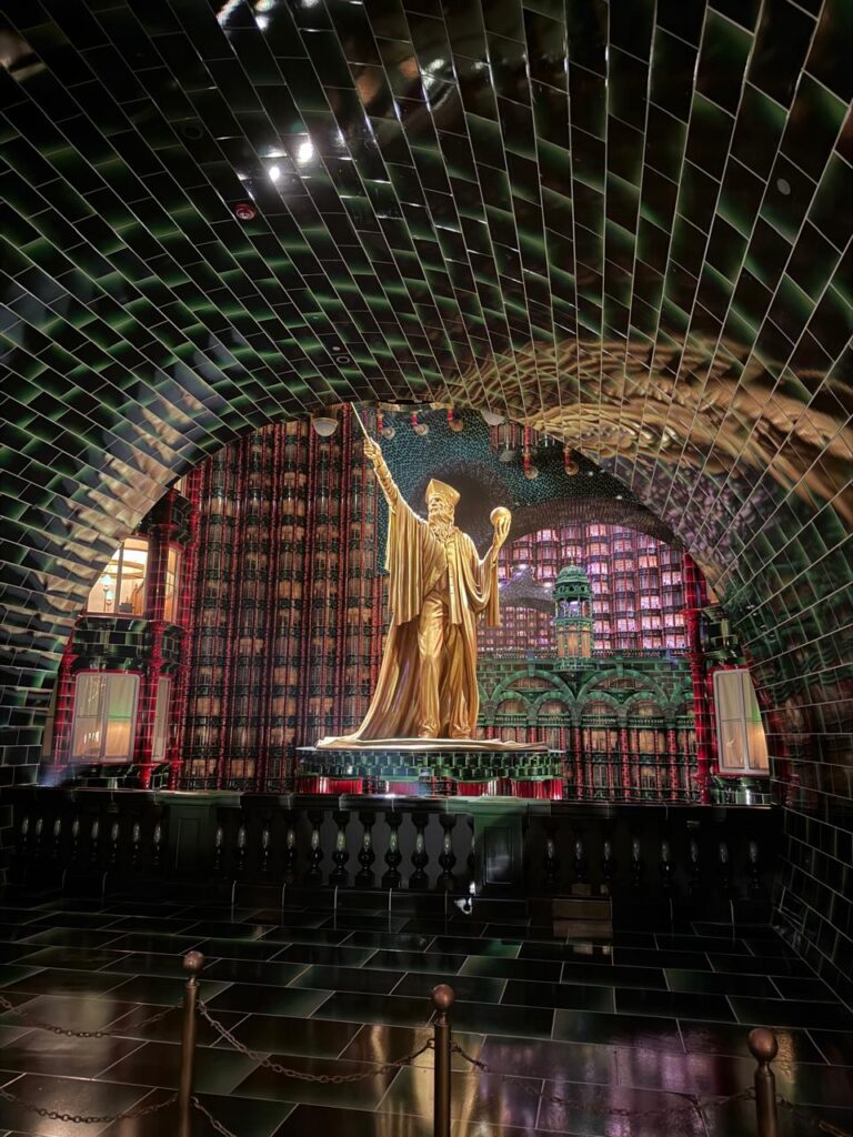 Saguão do Ministério da Magia com estátua dourada, na área Ministry of Magic do Epic Universe