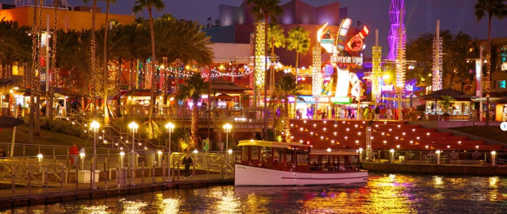 Universal CityWalk iluminado à noite, com restaurantes às margens do lago